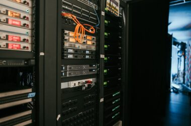 small dark equipment rack, patch panel, coiled orange cable