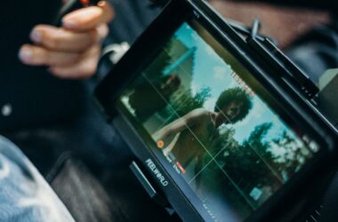 Field monitor held in lap, framing grid overlaid on live image