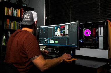 man in red t-shirt sitting in front of computer