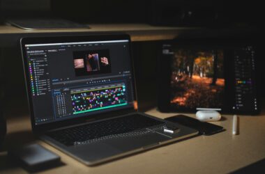 MacBook Pro with a Premiere Pro timeline open on a desk in a dark edit space