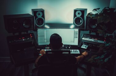 Editor at a dark desk with studio monitor speakers flanking the display