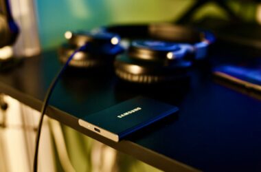Samsung T7 portable SSD on the edge of a dark desk next to headphones