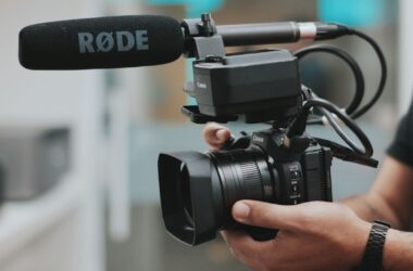 Hands holding Canon camcorder with RODE shotgun mic mounted