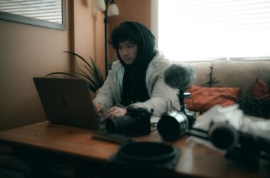 Shooter cutting on a laptop surrounded by bodies, lenses, mic