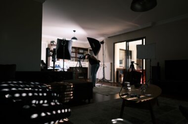 Living room turned shoot set: softboxes, camera on tripod, subject seated