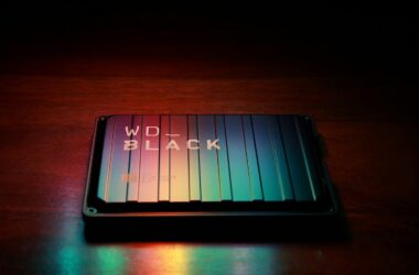 A WD Black portable hard drive on a dark wooden desk lit by colored light