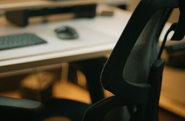 Ergonomic mesh office chair at a desk with a monitor in a dim room
