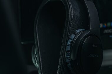 Black studio headphones resting on a stand on a dark desk