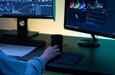 Editor working at a dual-monitor desk with warm bias lighting in a dark room