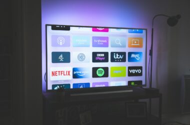 A large flat-screen TV glowing in a dark room with coloured bias lighting behind the panel