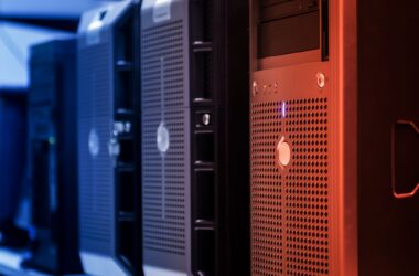 A row of black and silver tower servers with drive bays, lit blue on one side and red on the other in a dark room