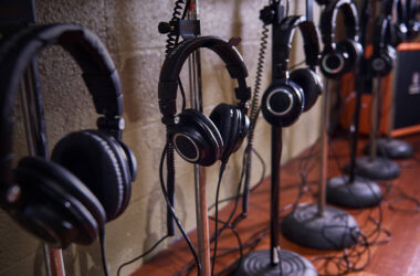 A row of Audio-Technica ATH-M50x headphones hanging on stands along a studio wall