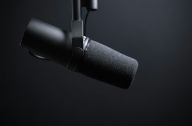 A black dynamic broadcast microphone on a boom arm against a dark background