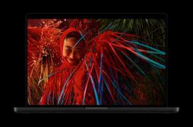 A space black MacBook Pro with PROLED XDR Display showing a red-lit portrait with neon streaks on screen