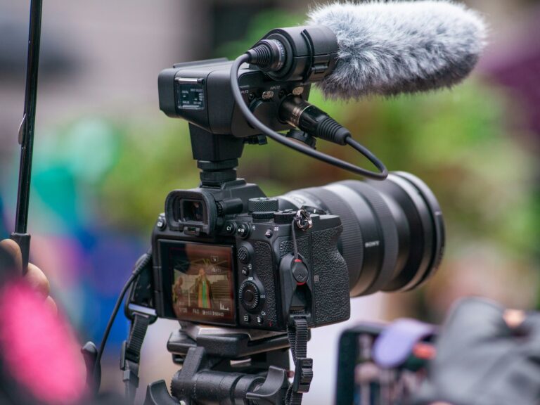 A Sony mirrorless camera on a tripod with an XLR audio adapter and shotgun microphone mounted on top