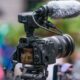 A Sony mirrorless camera on a tripod with an XLR audio adapter and shotgun microphone mounted on top