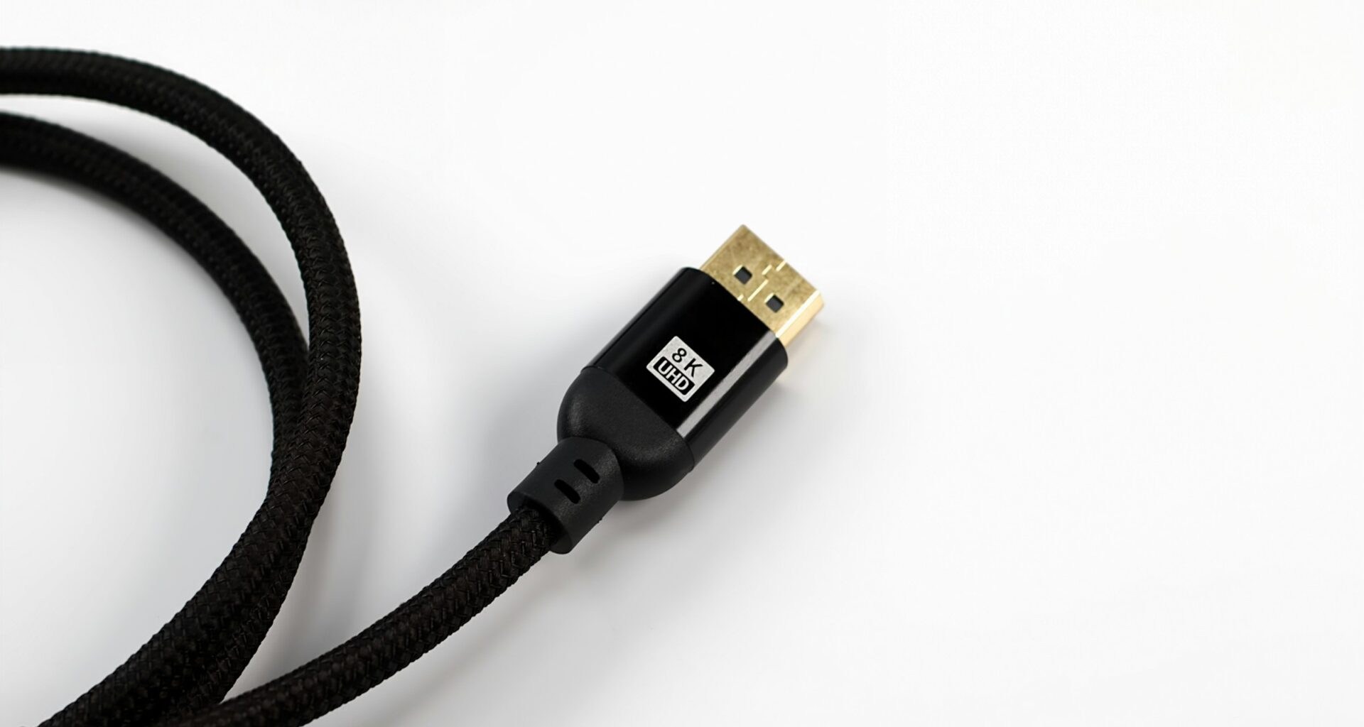 A braided HDMI cable with a gold connector on a white surface