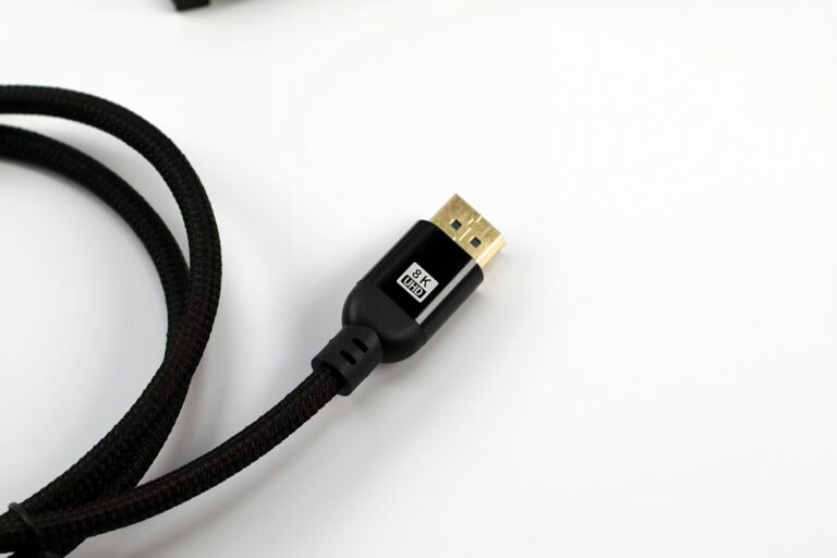 A braided HDMI cable with a gold connector on a white surface