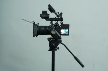 A Sony cinema camera rig on a fluid-head video tripod against a grey wall