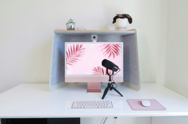 A webcam clipped to the top of a desktop monitor with a microphone on the desk