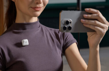 A creator filming herself with an iPhone, a white DJI Mic Mini transmitter clipped to her shirt