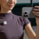 A creator filming herself with an iPhone, a white DJI Mic Mini transmitter clipped to her shirt