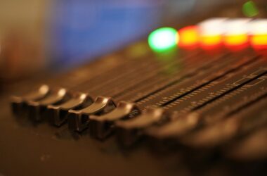 Close-up of faders and lit buttons on a control surface, shallow focus