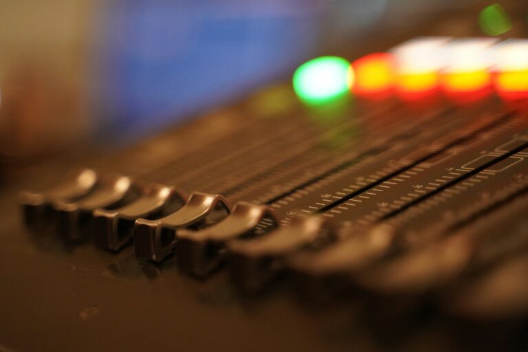 Close-up of faders and lit buttons on a control surface, shallow focus