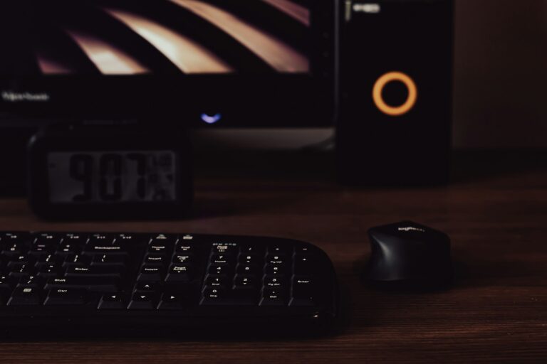 A dark editing desk at night with a mechanical keyboard, a mouse and a monitor