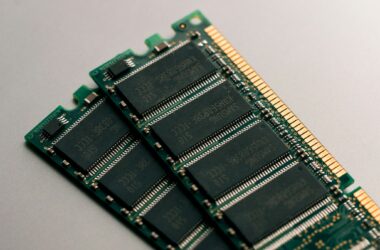 A DDR SODIMM memory module lying on a dark desk, chips and gold contacts in focus