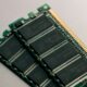 A DDR SODIMM memory module lying on a dark desk, chips and gold contacts in focus
