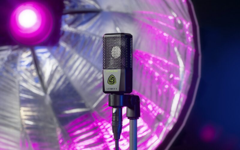 Lewitt large-diaphragm condenser microphone on a stand with an XLR cable, in front of a studio light