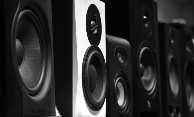 A row of black and gray studio monitor speakers on a wooden table