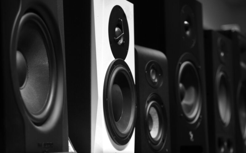 A row of black and gray studio monitor speakers on a wooden table